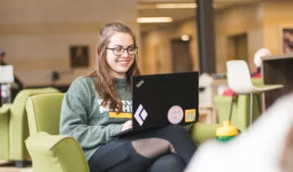 GC student sitting with her computer in Jamrich Hall seating area.